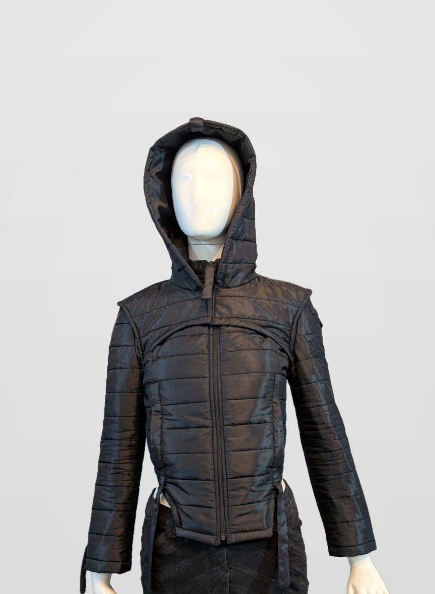 Black Nova Puffer — black futuristic hooded quilted puffer jacket on a mannequin, framed just below the jacket hem and side-strap ends